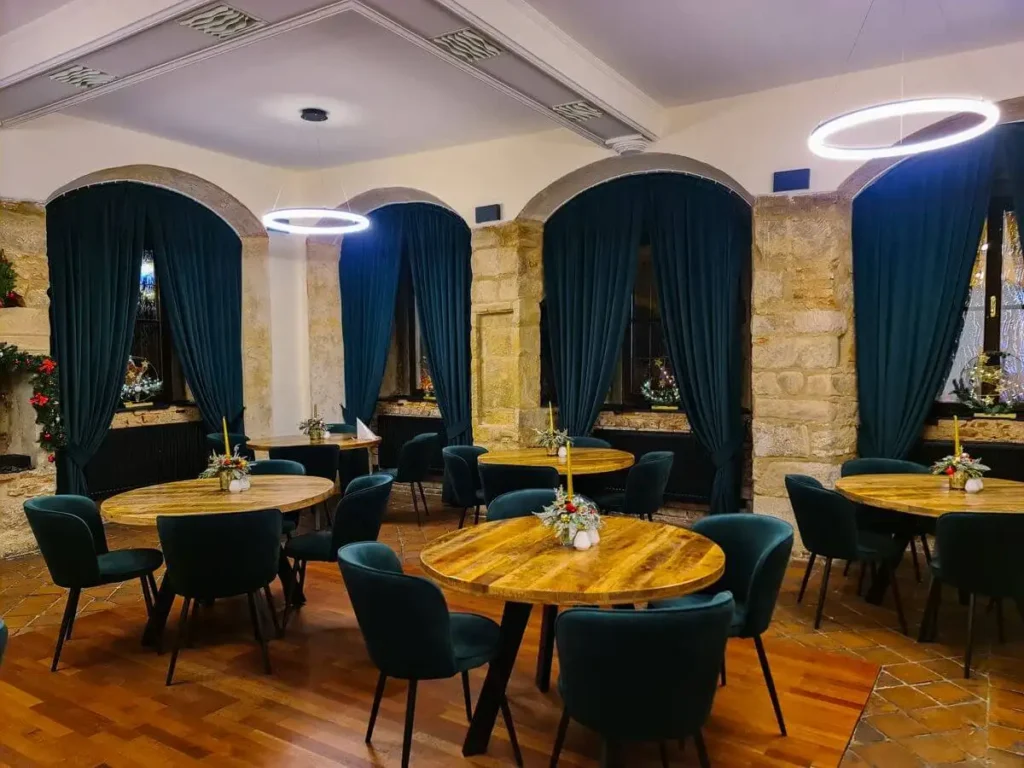 Main dining hall of a restaurant in Plzeň with stone features, round tables and elegant seating