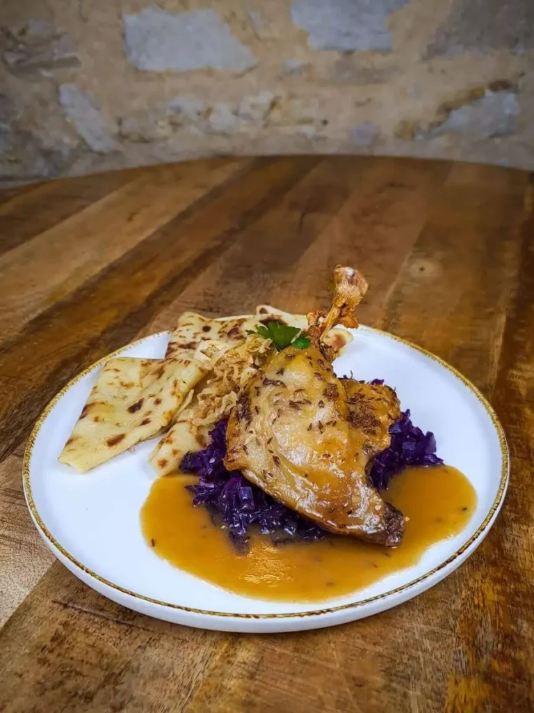 Konfitované kachní stehno podávané s červeným zelím, domácími lokšemi a omáčkou