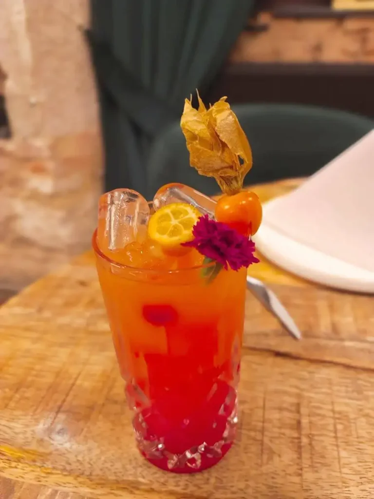 Tequila-Sunrise-Cocktail mit Eis, Zitrusfrüchten und Garnitur in einem hohen Glas serviert