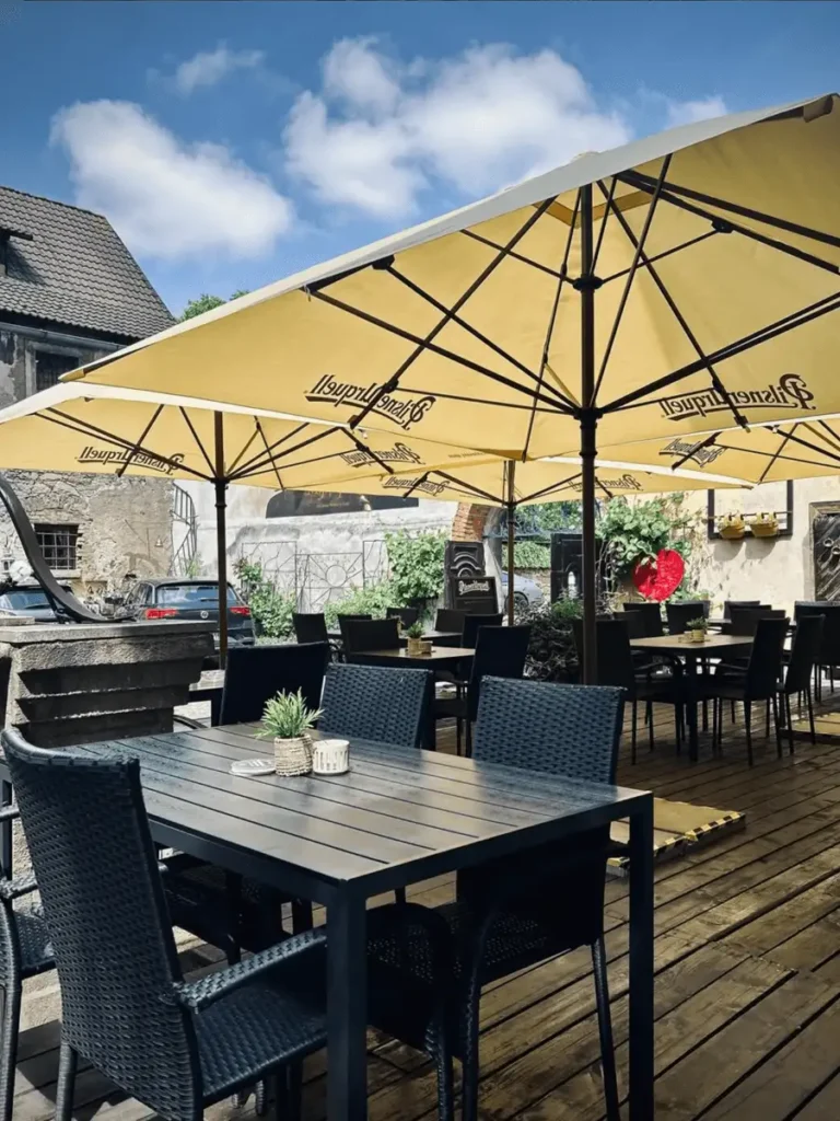 Venkovní zahrádka restaurace v Plzni s posezením, slunečníky a stoly pro hosty